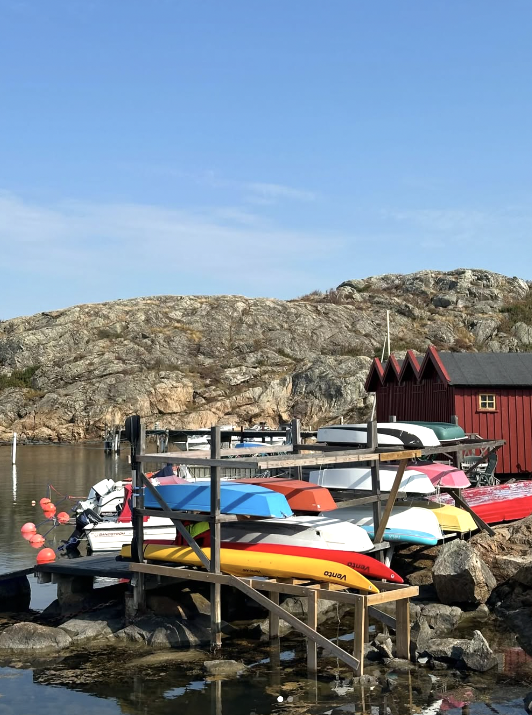 Båtar staplade vid bryggan med röd sjöbod i skärgården